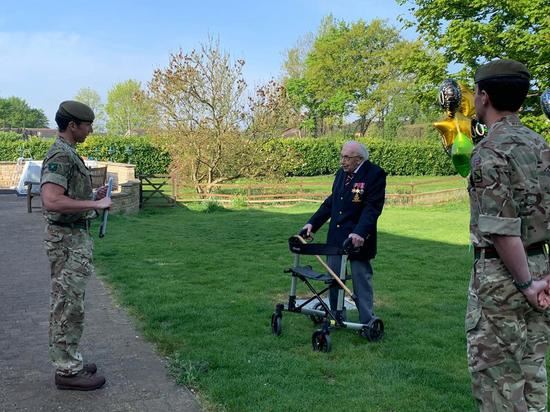 Tom Moore(C), a retired civil servant and Second World War veteran, talks with members of the 1st Battalion, the Yorkshire Regiment, after completing his final lap at his garden in Bedfordshire, Britain, on April 16, 2020. (Photo by Frances Haycock/MOD/Handout via Xinhua)