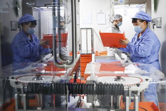 Staff members check by the automated light inspection machine at a packing line of inactivated COVID-19 vaccine of Sinovac Life Sciences Co., Ltd. in Beijing, capital of China, on Jan. 6, 2021. (Xinhua/Zhang Yuwei)